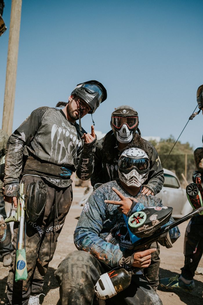 A group of paintball players wearing protective gear posing before a game. Outdoors setting.